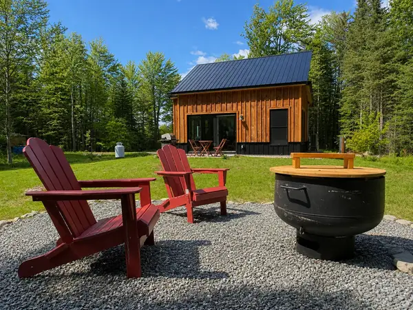 Red Adirondack chairs around the fire pit on a sunny summer day