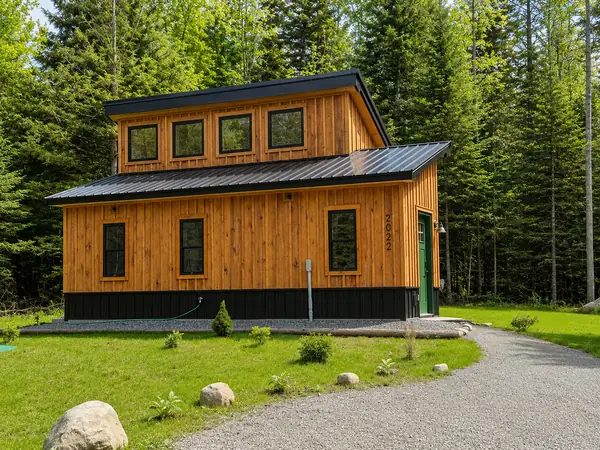 Simple Haven cabin in early summer with cedar siding and green metal roof