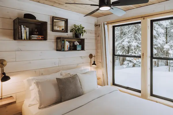 Bedroom with floor-to-ceiling windows looking into the snowy forest