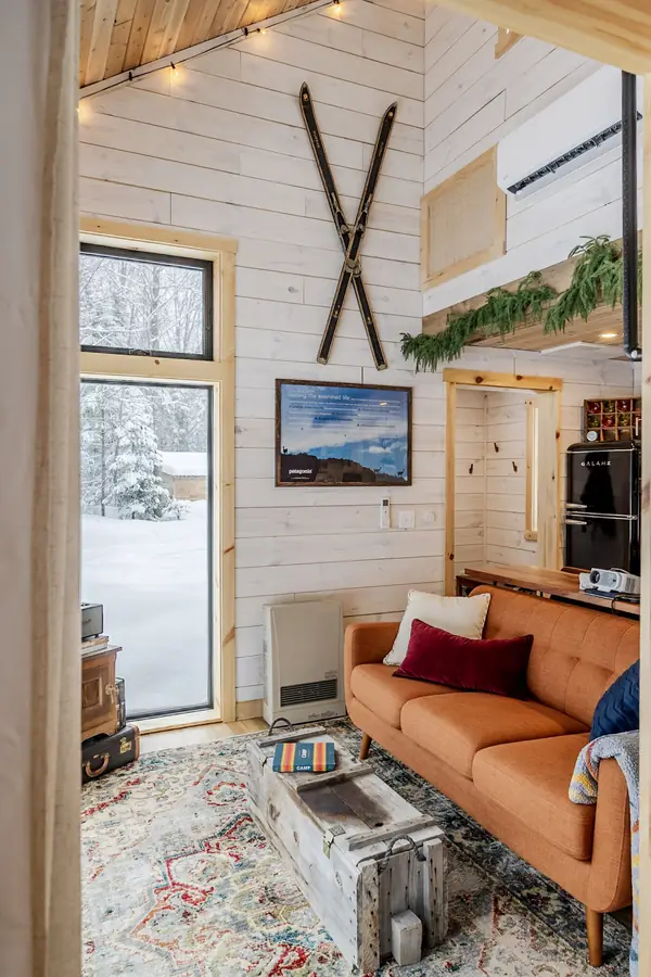 Living room with leather couch, wood stove, and loft ladder