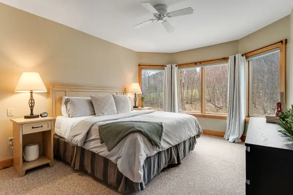King bed with wall of windows looking out to the forest