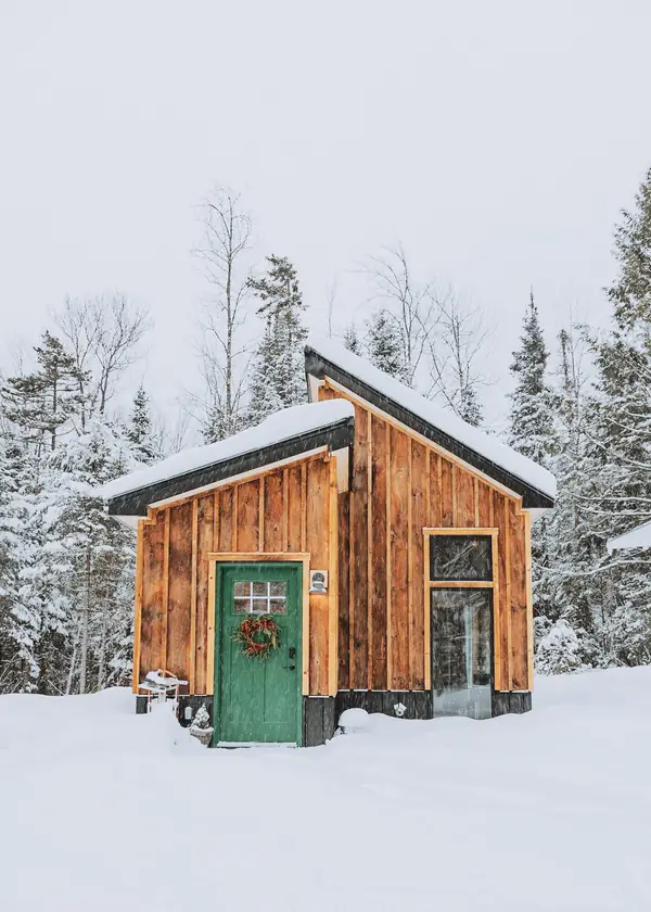 Front exterior of the cabin with green door and snow-covered ground