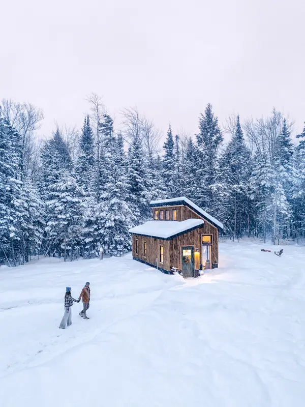 Aerial view of Simple Haven cabin glowing at dusk in a snowy Vermont clearing