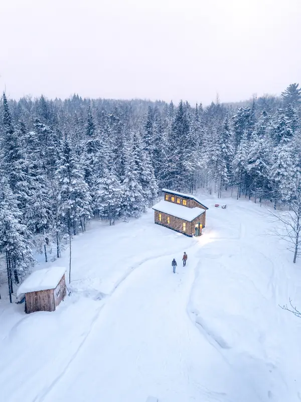 Aerial view of guests walking toward the cabin in fresh snow