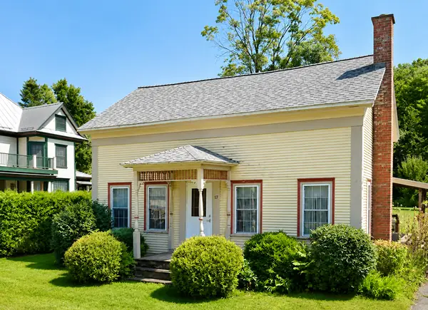 Side view of the cottage with green lawn and gardens