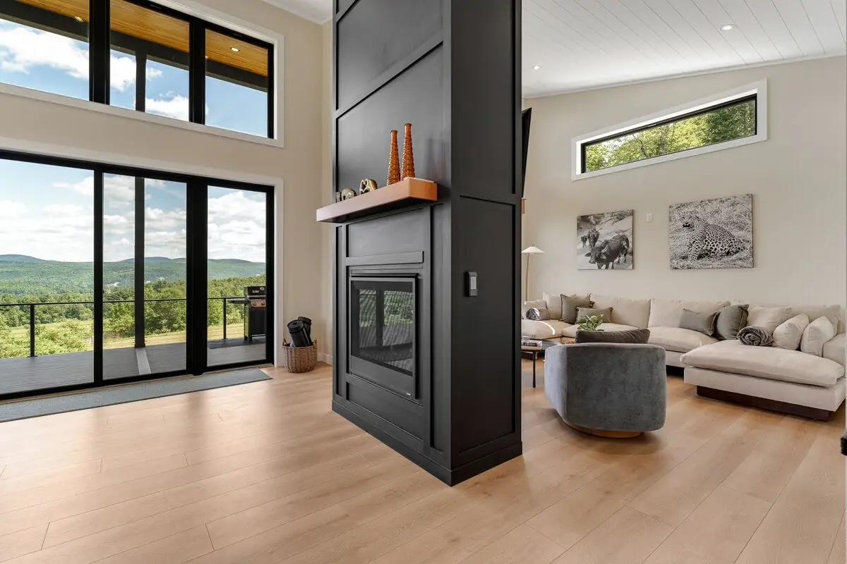 Living room with double-sided gas fireplace and panoramic Vermont mountain views