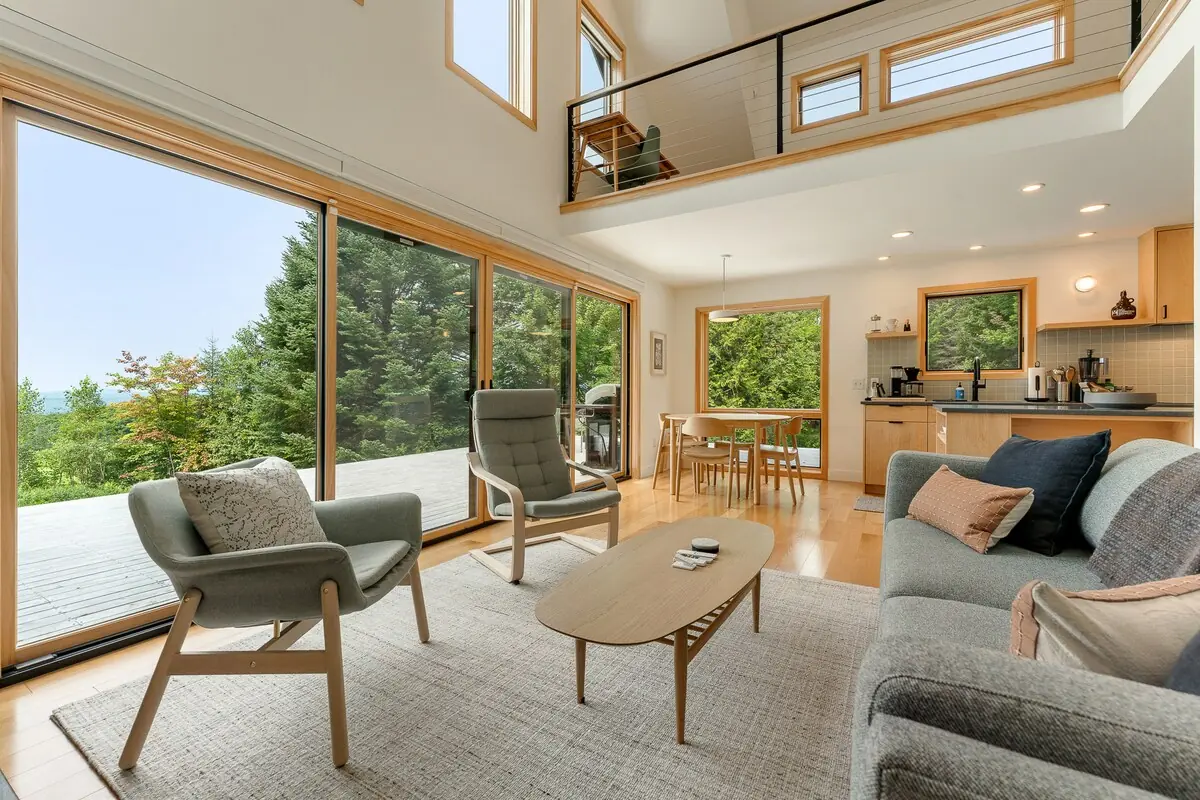 Vaulted cabin living room with walls of glass looking over the Vermont hills