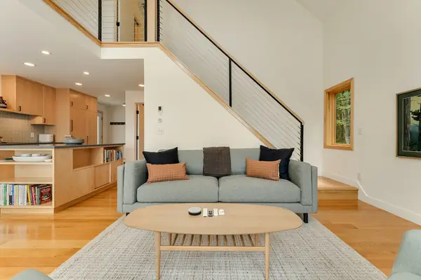 Sofa facing tall windows and the surrounding forest